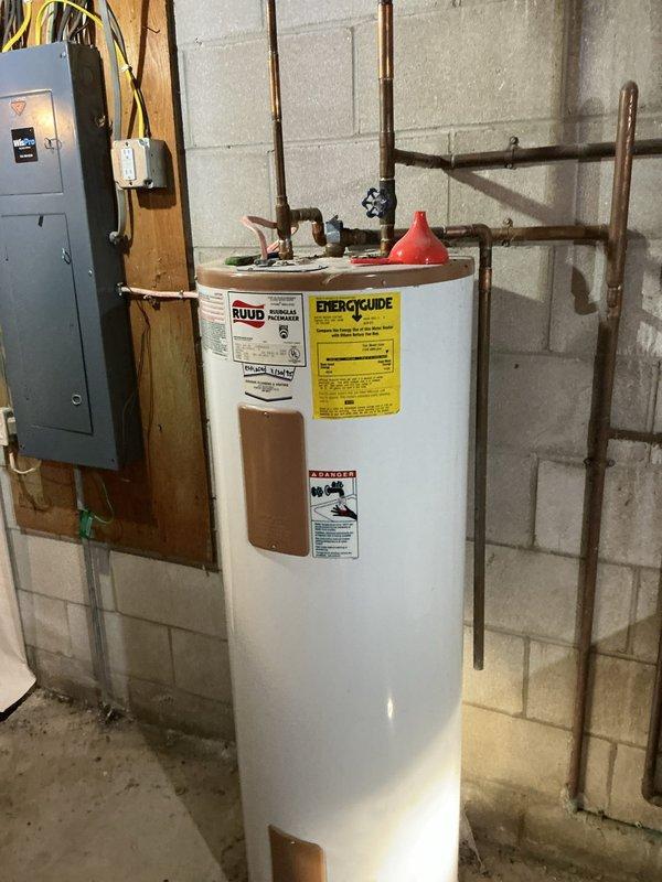 Relocated existing Ruud tanked water heater and temporarily reconfigured plumbing system to accommodate basement drainage tile installation by separate contractor. Disconnected and capped laundry tub drain, removed utility sink, and relocated multiple water supply lines to clear work area while maintaining active water service to residence. Re-piped water heater connections with copper piping to new temporary location, ensuring all connections remained functional and code-compliant during drainage work phase.