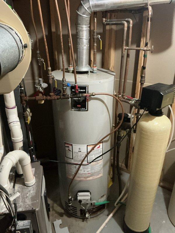 Successfully completed water heater replacement in basement utility room. Removed existing water heater unit and installed new tall white residential water heater with proper connections to overhead ductwork and copper supply lines. Installation included mounting control panel near top of unit, connecting all required plumbing fixtures, and ensuring proper integration with existing HVAC system, water softener, and filtration equipment. All manufacturer specifications and safety requirements were followed during installation, with documentation photos submitted for inspection approval.