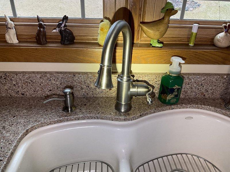 Responded to service call for leaking kitchen faucet and reverse osmosis faucet. Replaced worn Moen single-handle cartridge in main kitchen faucet to eliminate leak at base. Installed customer-supplied non-air gap reverse osmosis faucet on countertop. Tested both faucets for proper operation and verified all connections were secure with no leaks present.