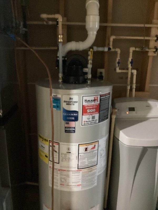 Responded to warranty call for loud noise from Bradford White water heater audible throughout home. Diagnosed vibration originating from unsecured PVC venting in finished soffit rather than blower motor assembly. Verified blower motor operation within normal parameters. Homeowner declined recommendation to open soffit for proper venting securement. Documented existing conditions with photos showing water heater installation, venting configuration, and surrounding mechanical systems.