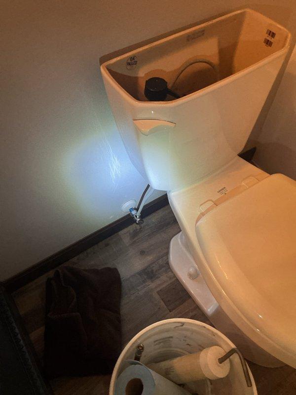 Responded to emergency water leak at toilet fixture that had caused flooding in rear of residence. Upon arrival, found customer had already shut off angle stop valve to isolate leak. Identified failed water supply line connection at toilet tank inlet as source of rapid leak. Removed defective braided supply line and installed new flexible water supply connector with proper compression fittings. Restored water supply, tested connections under full pressure, and verified complete seal with no leakage present.