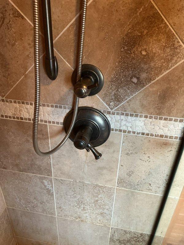 Responded to service call for shower leaking from both rain head and standard shower head. Diagnosed issue as faulty valve cartridge requiring replacement. Installed manufacturer replacement cartridge repair kit for standard brand faucet (Moen/Delta compatible). Removed existing cartridge from dual-handle shower valve system with bronze finish fixtures mounted on decorative tile surround. Replaced with 100% manufacturer-specified cartridge to restore proper water control and eliminate leaking condition. Tested operation of both shower heads post-installation to verify complete leak resolution and proper flow control through diverter valve. Repair completed in approximately 30 minutes with all fixtures functioning properly.