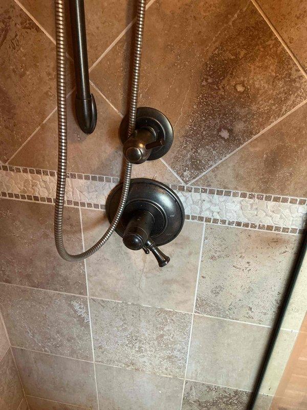 Responded to service call for shower leaking from both rain head and standard shower head. Diagnosed issue as faulty valve cartridge requiring replacement. Installed manufacturer replacement cartridge repair kit for standard brand faucet (Moen/Delta compatible). Removed existing cartridge from dual-handle shower valve system with bronze finish fixtures mounted on decorative tile surround. Replaced with 100% manufacturer-specified cartridge to restore proper water control and eliminate leaking condition. Tested operation of both shower heads post-installation to verify complete leak resolution and proper flow control through diverter valve. Repair completed in approximately 30 minutes with all fixtures functioning properly.