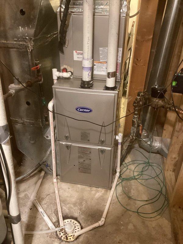 Performed comprehensive safety inspection and tune-up on 1-year-old Carrier high-efficiency furnace in response to reports of faint exhaust odor in mechanical room and icicle formation on exterior exhaust pipe. Conducted thorough combustion analysis and verified all system components including flame sensor, igniter, inducer motor, and control board were operating within manufacturer specifications. Inspected all utility room gas piping with combustible gas detector and confirmed no leaks present. Evaluated venting system for proper draft and condensate drainage to address icicle formation concern. Replaced slightly dirty air filter to restore optimal airflow. Verified furnace burner operation with proper flame characteristics and confirmed safe combustion process with no carbon monoxide spillage into living spaces. All safety controls tested and functioning correctly. System confirmed operating safely with no immediate concerns identified.