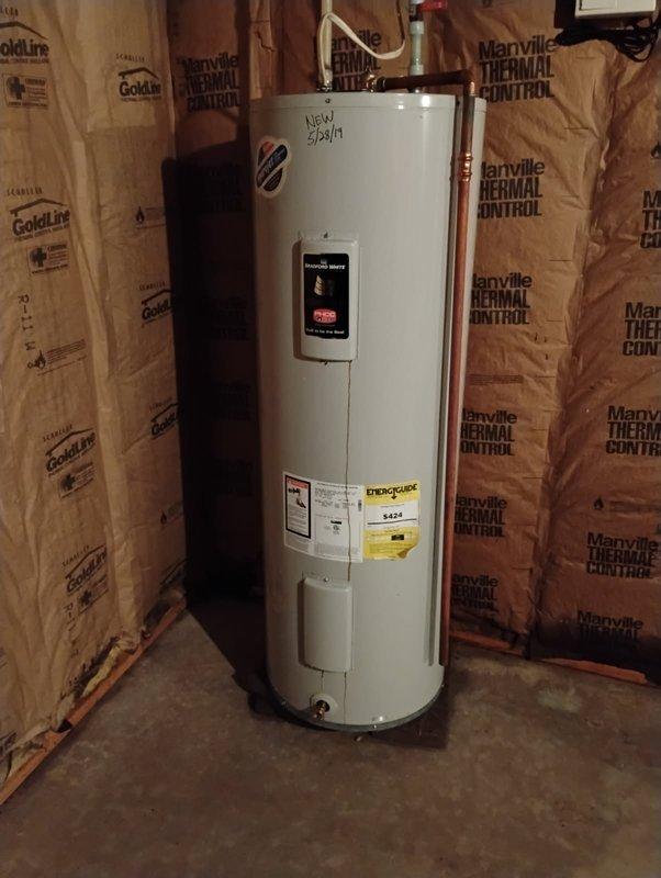Responded to emergency call for leaking 50-gallon electric Bradford White water heater installed in May 2019. Upon arrival, found unit actively spraying water from top connections, indicating catastrophic failure of upper plumbing components or internal tank breach. Due to severity of leak and age of unit, determined replacement was most cost-effective solution. Removed failed water heater and installed new Bradford White 50-gallon electric water heater in basement utility area. Connected all copper supply lines, installed new pressure relief valve with proper discharge piping, verified all electrical connections to code, and tested unit for proper operation and leak-free performance before completing installation.