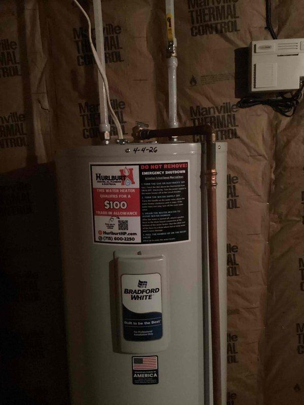 Responded to emergency call for leaking 50-gallon electric Bradford White water heater installed in May 2019. Upon arrival, found unit actively spraying water from top connections, indicating catastrophic failure of upper plumbing components or internal tank breach. Due to severity of leak and age of unit, determined replacement was most cost-effective solution. Removed failed water heater and installed new Bradford White 50-gallon electric water heater in basement utility area. Connected all copper supply lines, installed new pressure relief valve with proper discharge piping, verified all electrical connections to code, and tested unit for proper operation and leak-free performance before completing installation.