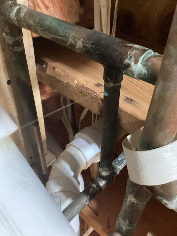 Responded to emergency water leak in basement caused by pinhole leaks in corroded copper supply line. Water was shut off to the home upon arrival. Performed temporary repair to damaged copper piping section to restore water service to the residence. Extensive corrosion and green patina observed on existing copper pipes indicating age-related deterioration. Installed flexible copper corrugated pipe section with brass compression fittings to bypass the compromised area. Secured new piping to structural framing with appropriate fasteners. Tested repair for leaks and restored water supply to the home. Provided estimate for complete copper repipe system replacement due to widespread corrosion throughout existing plumbing infrastructure.