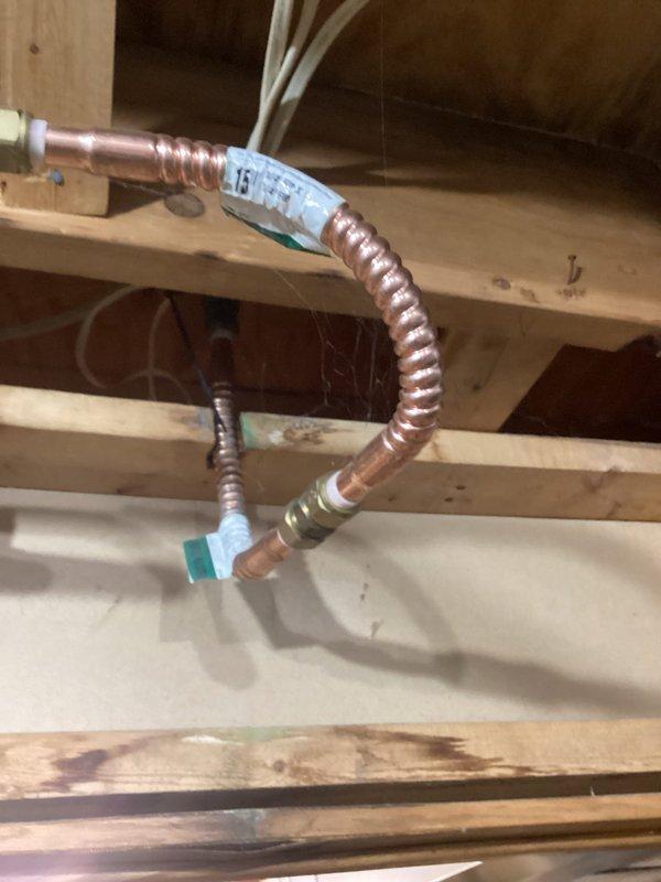 Responded to emergency water leak in basement caused by pinhole leaks in corroded copper supply line. Water was shut off to the home upon arrival. Performed temporary repair to damaged copper piping section to restore water service to the residence. Extensive corrosion and green patina observed on existing copper pipes indicating age-related deterioration. Installed flexible copper corrugated pipe section with brass compression fittings to bypass the compromised area. Secured new piping to structural framing with appropriate fasteners. Tested repair for leaks and restored water supply to the home. Provided estimate for complete copper repipe system replacement due to widespread corrosion throughout existing plumbing infrastructure.