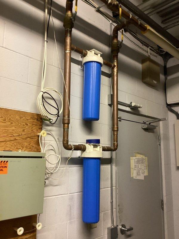 Responded to commercial facility reporting no hot water at multiple points throughout the building. Upon arrival, performed diagnostic assessment of Bradford White tanked water heater located in riser room. Found unit currently operational and producing hot water, though previous element replacement occurred approximately 6-7 years ago and overall unit age is unknown. Documented existing 50-gallon water heater system with associated copper piping, filtration equipment, and electrical service connections. Verified hot water delivery restored to building. Photographed installation for assessment and recommended future water heater replacement due to age and history of heating element failure.