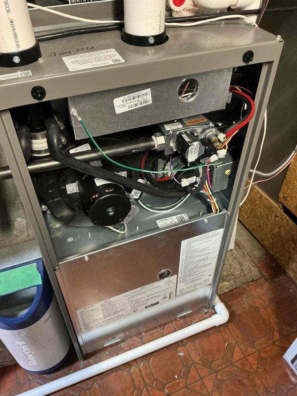 Responded to service call for Lennox EL21KLV-036-230A01 heat pump and EL297UH070X-V36B-02 furnace experiencing defrost cycle tempering issues. Customer reported consistent cold air blasts during defrost cycles in cold weather, with register air temperatures dropping to 52°F and furnace outlet air at 42°F. Investigated auxiliary heat tempering function during defrost cycles and found burner igniting for only 8-12 seconds with minimal temperature rise before shutting off, contrary to standard defrost tempering sequence of 75 seconds on/90 seconds off cycling. Inspected gas valve operation, blower motor function, and control board settings. Reviewed thermostat programming on Lennox S40 and verified heat pump defrost initiation parameters. Documented system performance with photographs of internal components including gas valve assembly, blower motor, electrical connections, and control wiring. Evaluated defrost cycle timing and auxiliary heat staging to determine root cause of inadequate 