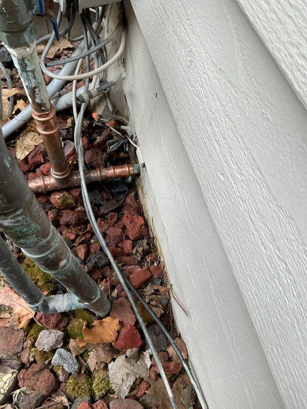 Responded to follow-up appointment for outdoor irrigation system leak. Upon inspection, identified a pinhole leak in three-quarter inch copper waterline caused by grounding clamp damage just after the pipe exited the building. The grounding clamp had created pressure and corrosion on the copper pipe, resulting in water seepage at the sprinkler system's manifold area. Performed repair of the damaged three-quarter inch waterline section, replacing the compromised copper pipe segment and ensuring proper clearance from the grounding clamp to prevent future contact damage. Verified all connections were secure and tested the irrigation system for proper water flow and absence of leaks following repair completion.