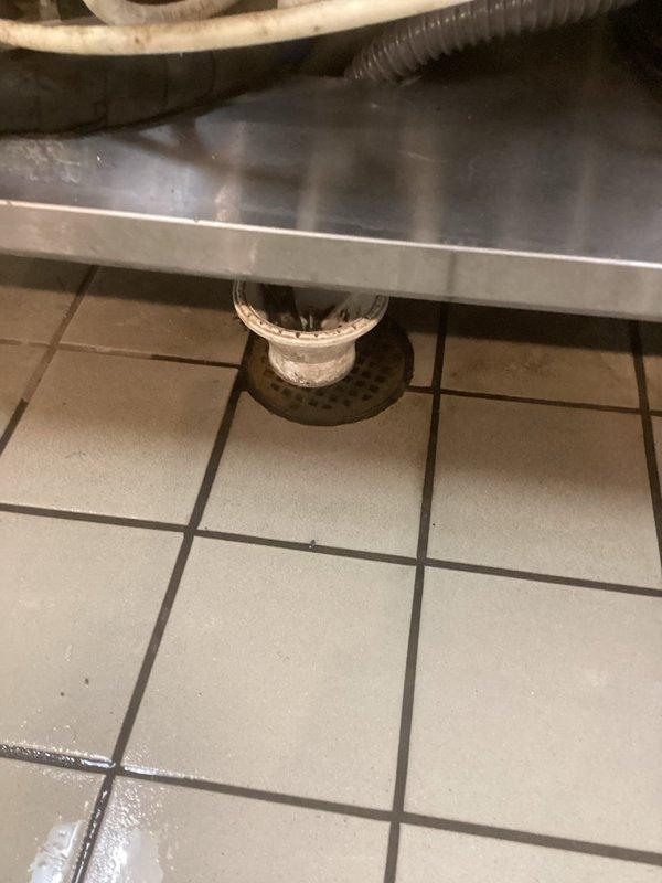 Responded to main drain backup in commercial kitchen facility. Floor drain beneath refrigeration equipment was clogged with syrup buildup. Used cable machine to clear blockage and restore proper drainage. Previous service had been performed for similar issue, indicating recurring problem with syrup disposal in this location.