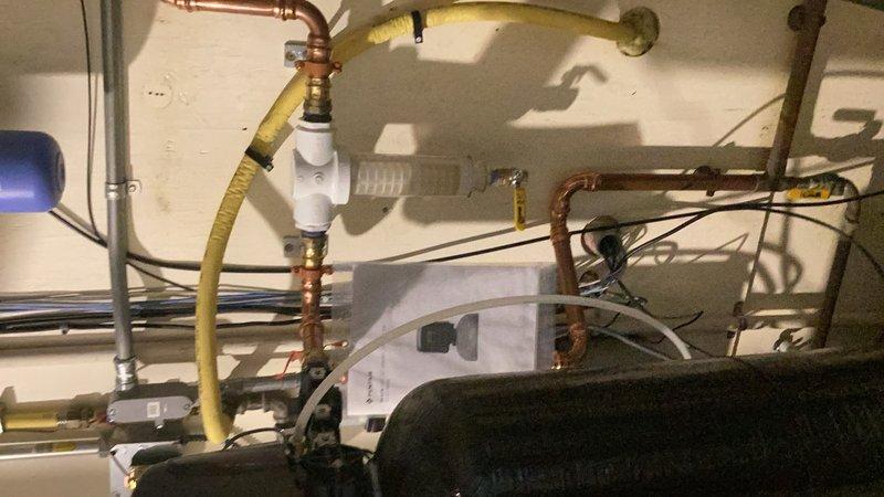 Completed comprehensive plumbing inspection of water heater installation, examining copper supply lines, gas connections, and associated components. Documented existing corrosion on copper piping with visible patina formation, verified proper installation of yellow flexible gas line with appropriate brass fittings and PVC connections, and assessed HVAC refrigeration system equipment including pressure gauges, hoses, and monitoring devices for proper operation and compliance with code requirements.