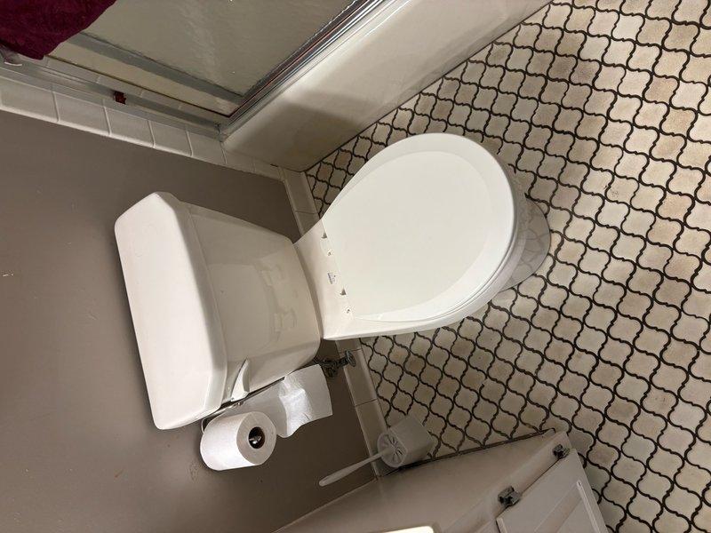 Responded to a callback for a hallway bathroom toilet that was periodically running and leaking. Upon inspection, discovered the flapper had become dislodged from the flush valve hinge. Reinstalled the flapper and properly secured it to the flush valve assembly to restore proper operation. Additionally, documented existing bathroom fixtures with photographs for future estimate preparation, including hallway bathroom fixtures and primary shower trim replacement.