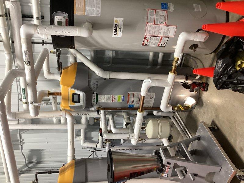 Performed inspection of residential plumbing system to verify pipe sizing, confirming 1-1/2" L copper piping installation. Documented existing HVAC and plumbing configuration including ball valve connections, PVC supply lines, and mechanical equipment layout. Provided consultation regarding electronic anode rod installation options for water heater system.