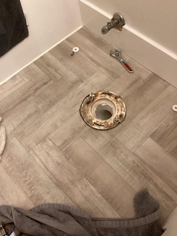 Responded to water leak at back of toilet tank that persisted despite previous seal replacements. Upon inspection, identified that existing 14-inch elongated toilet was incompatible with the rough-in measurement. Flange measurement confirmed 10-inch rough-in rather than standard 12-inch configuration. Removed old toilet and observed corroded, rusted flange showing signs of long-term water exposure and deterioration. Replaced existing oversized toilet with properly sized 10-inch rough-in elongated toilet to match actual flange positioning and bathroom space constraints. Installed new unit, verified proper seal and mounting, tested flush operation, and confirmed no leakage from tank or base connections.