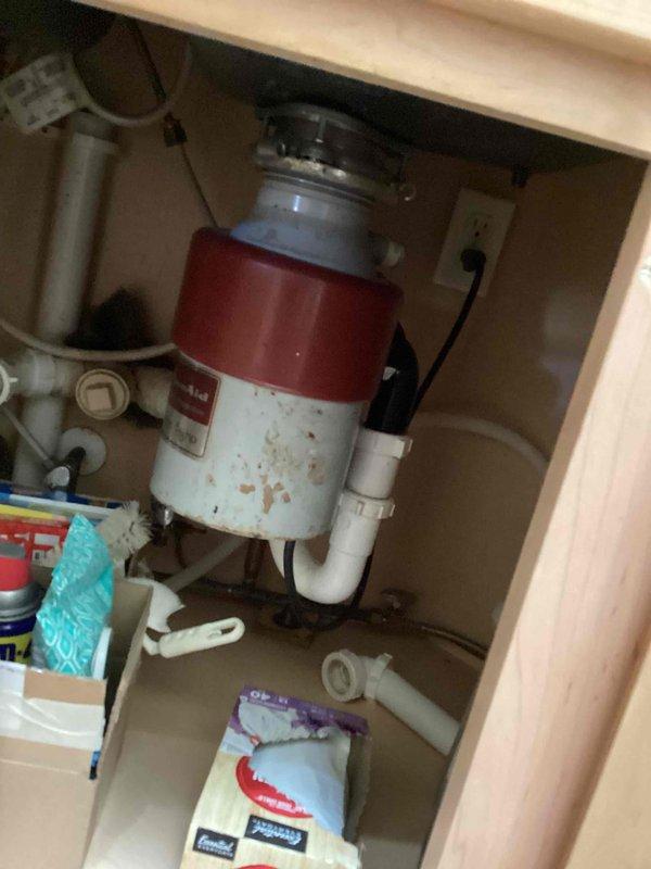 Responded to service call for non-functioning garbage disposal producing humming noise. Upon inspection, diagnosed unit as seized and inoperable. Assessed existing disposal unit mounted beneath kitchen sink, noting age-related wear and discoloration on housing. Verified electrical connection at cabinet outlet and confirmed motor engagement without blade rotation, indicating internal mechanical failure. Provided estimate for disposal replacement options.