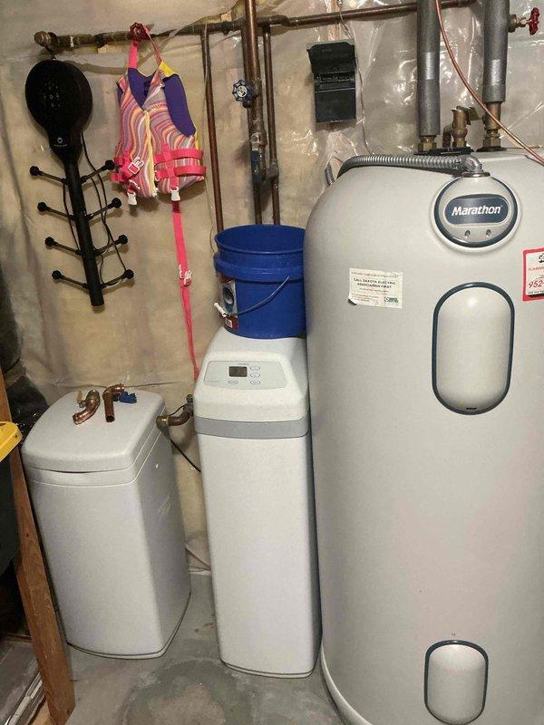 Responded to service call for water heater with no hot water production. Upon arrival, performed diagnostic inspection of Marathon electric water heater in basement utility area. Identified active leak from tank and failed heating element as primary issues. Due to tank integrity compromise and leak severity, determined unit was beyond economical repair. Documented equipment condition with photographs showing water heater installation, surrounding plumbing connections, and leak evidence. Provided customer with replacement options and estimates for new water heater installation.