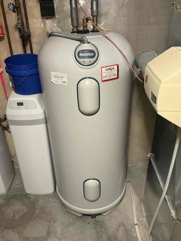 Responded to service call for water heater with no hot water production. Upon arrival, performed diagnostic inspection of Marathon electric water heater in basement utility area. Identified active leak from tank and failed heating element as primary issues. Due to tank integrity compromise and leak severity, determined unit was beyond economical repair. Documented equipment condition with photographs showing water heater installation, surrounding plumbing connections, and leak evidence. Provided customer with replacement options and estimates for new water heater installation.