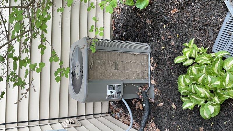 Performed comprehensive AC tune-up on outdoor condensing unit, including cleaning and inspection of all components. Unit showed signs of age with accumulated debris on top surface and surrounding area; removed organic matter and cleaned exterior housing. Verified proper operation of cylindrical barrel-style condenser with horizontal ribbed fins, checked refrigerant levels, inspected electrical connections, and confirmed adequate airflow through ventilation grilles. Noted dryer vent positioned in close proximity to AC unit and verified proper clearance for system operation. All components functioning within normal parameters upon completion of maintenance service.