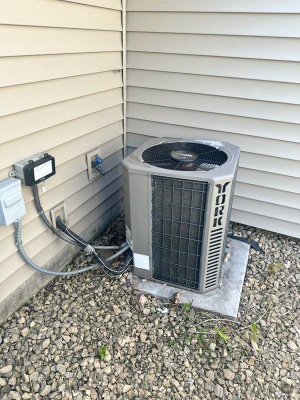 Responded to no cooling call on 22-year-old York R22 air conditioning system. Upon arrival, discovered customer had recently replaced thermostat but failed to connect wiring to outdoor condensing unit, resulting in complete system failure. Diagnosed wiring issue and properly reconnected thermostat wires to restore communication between indoor and outdoor units. Tested system operation and confirmed air conditioning unit now powers on and cycles properly. Noted outdoor condenser coil requires cleaning due to dirt and debris accumulation affecting efficiency. Advised customer of system age, R22 refrigerant phase-out implications, and replacement options. Customer declined replacement recommendations and elected to perform condenser coil cleaning independently. System restored to operational status with proper thermostat wiring configuration.