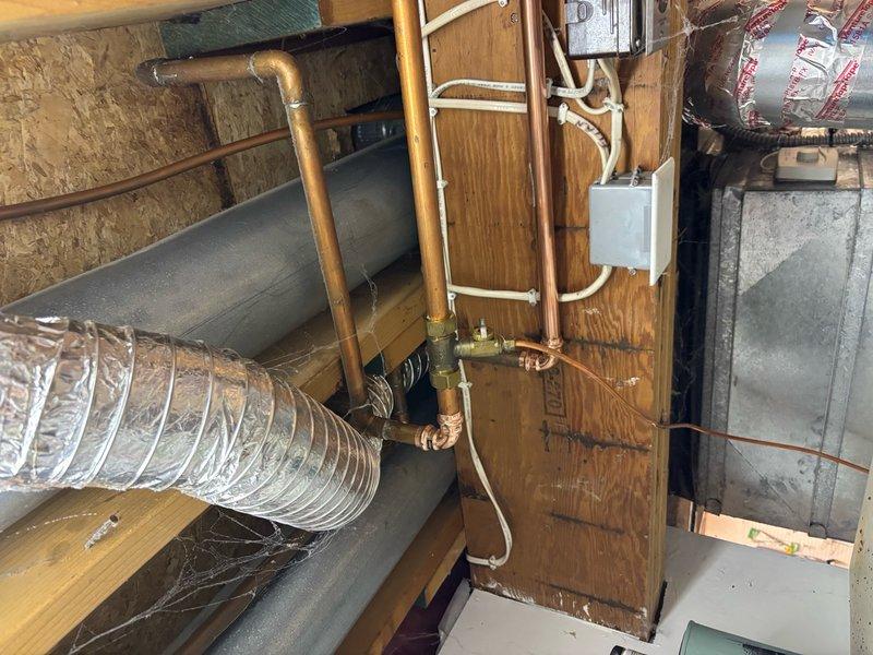 Removed and disposed of existing natural draft water heater, capped 3/8" gas line at furnace and 4" ventilation. Installed Bradford White G2 Series 65-gallon electric hybrid heat pump water heater in new location next to utility sink. Extended 3/4" water inlet and outlet lines to new location and connected to system with code-compliant isolated shut-off valves. Installed condensate line routed to utility sink. Ran dedicated 240V circuit from electrical panel in garage, through accessible attic space, down shared wall into utility room (approximately 40' total run). Performed panel modifications to accommodate new circuit on full panel, installed disconnect adjacent to water heater, completed all wiring connections at panel, disconnect, and water heater. Programmed and configured water heater to specifications. Completed virtual inspection which passed. Verified all connections leak-free and confirmed system operational upon power-up.
