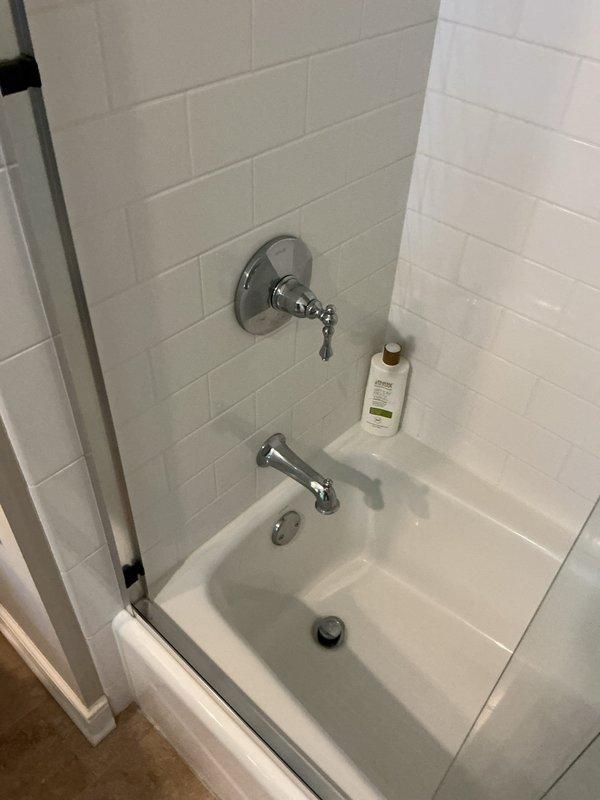 Responded to service call for bathroom fixture evaluation and tub spout malfunction. Upon inspection, identified failed diverter mechanism in chrome tub spout causing active leak. The diverter, which controls water flow between the tub spout and showerhead, showed significant deterioration and was no longer functioning properly. Documented existing bathroom configuration featuring white subway tile surround and chrome fixtures. Photographed the leaking tub spout assembly and provided customer with replacement options and estimates for new fixture installation to resolve the diverter failure and restore proper function to the tub and shower system.