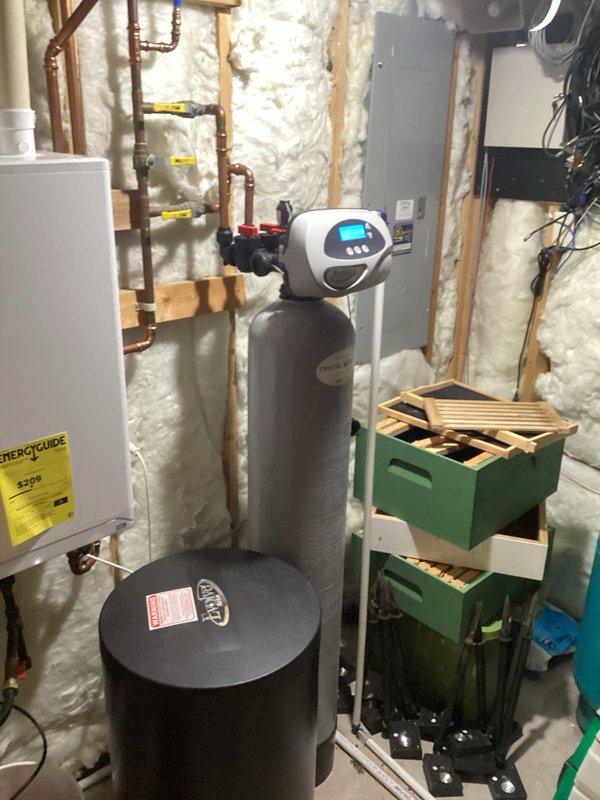 Completed plumbing inspection of residential property with focus on second-floor bathroom. Confirmed that bathtub overflow drain is not connected to waste piping system, creating potential for water damage and code violation. Documented existing plumbing infrastructure including water softener system, water heater, and associated copper supply lines in basement mechanical room.