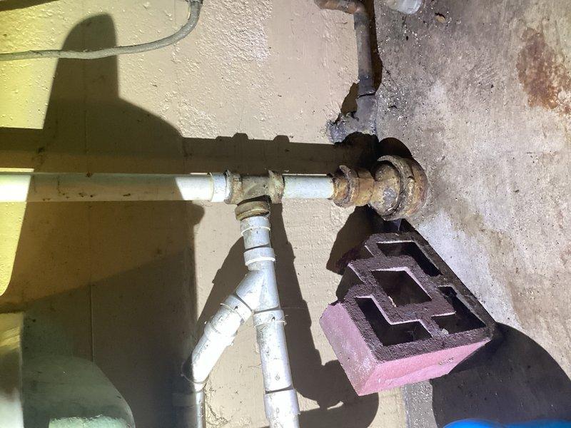 Responded to no hot water complaint at property with wood boiler system integrated with water heater. Upon arrival, diagnosed tripped thermostat on water heater unit. Reset thermostat to restore hot water functionality. Inspected exterior plumbing connections and gas infrastructure mounted on building exterior, noting existing corrosion on metal components. Documented crawl space plumbing installation showing PVC pipes with rubber couplings and evidence of moisture exposure causing rust staining on metal fittings. System restored to normal operation following thermostat reset.
