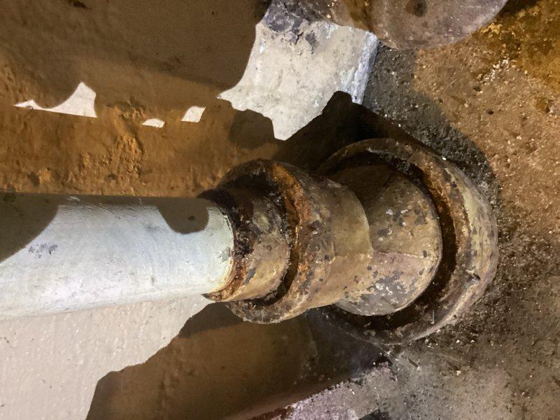 Responded to no hot water complaint at property with wood boiler system integrated with water heater. Upon arrival, diagnosed tripped thermostat on water heater unit. Reset thermostat to restore hot water functionality. Inspected exterior plumbing connections and gas infrastructure mounted on building exterior, noting existing corrosion on metal components. Documented crawl space plumbing installation showing PVC pipes with rubber couplings and evidence of moisture exposure causing rust staining on metal fittings. System restored to normal operation following thermostat reset.