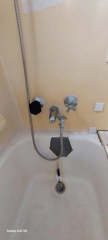 Completed follow-up phone consultation to discuss previously provided estimates from 5/11 regarding bathroom shower installation and plumbing fixture upgrades. Reviewed photographic documentation showing existing handheld shower assembly with chrome-plated flexible hose, wall-mounted holder bracket, dual control valve system with octagonal and star-shaped knobs, and various mounting points on pale yellow tiled walls requiring fixture installation or replacement.