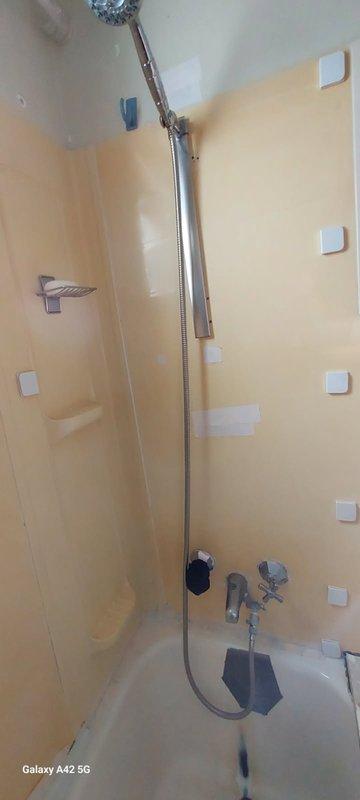 Completed follow-up phone consultation to discuss previously provided estimates from 5/11 regarding bathroom shower installation and plumbing fixture upgrades. Reviewed photographic documentation showing existing handheld shower assembly with chrome-plated flexible hose, wall-mounted holder bracket, dual control valve system with octagonal and star-shaped knobs, and various mounting points on pale yellow tiled walls requiring fixture installation or replacement.