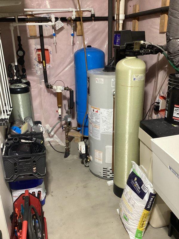 Completed comprehensive plumbing system inspection for family residence with no known issues reported. Thoroughly examined water heater, water softener system, pressure tank, well pump components, and associated plumbing connections including valves, gauges, and piping throughout mechanical room. All equipment found operating within normal parameters with no deficiencies identified.