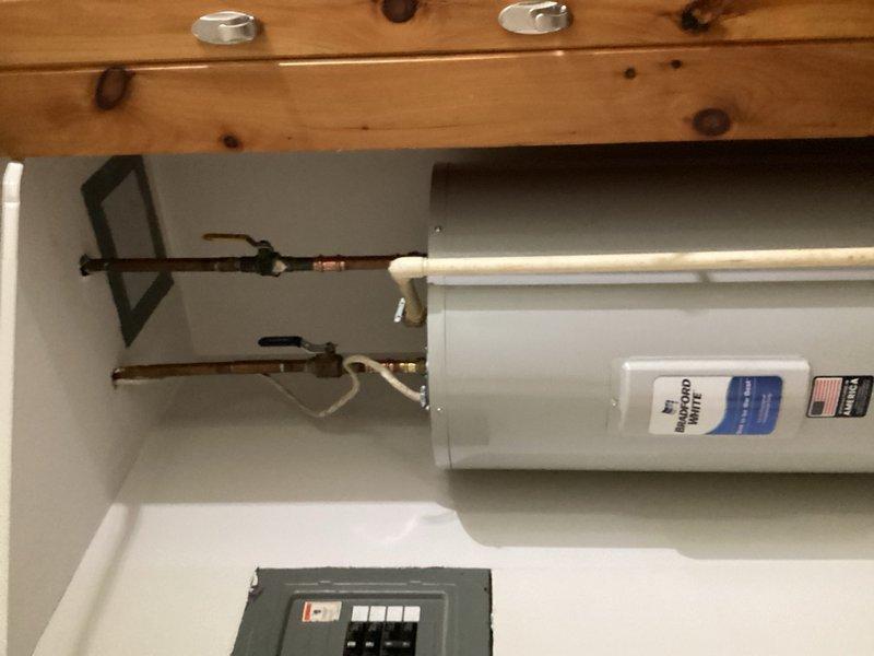 Responded to water heater leak causing damage to adjacent wall and intermittent water pressure issues resulting in 1-2 minute water cutoffs. Upon inspection, discovered water heater leaking from multiple locations and pressure switch nipple completely plugged with sediment buildup. Removed and replaced failed tanked water heater unit with new installation, including all necessary copper pipe connections and fittings. Installed new pressure switch assembly with nipple to restore proper system pressure regulation. Verified temperature and pressure relief valve operation and tested all connections for leaks. System restored to full functionality with consistent water pressure and no active leaks.
