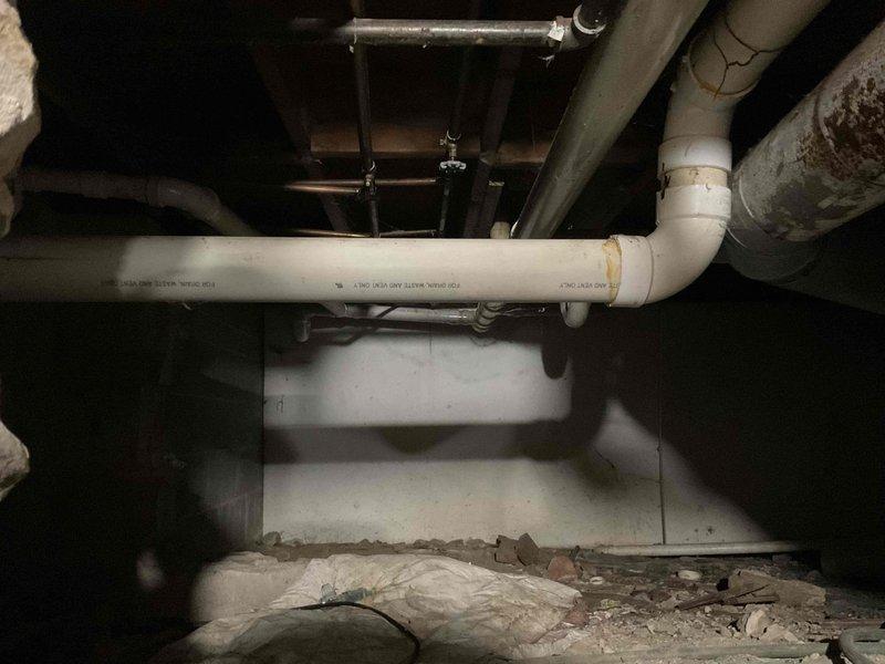 Responded to service call for 40-gallon tanked water heater displaying error code 61 on 8-year-old unit. Conducted diagnostic inspection of water heater system and associated components. Inspected exterior foundation penetrations including water heater venting and combustion air intake connections. Examined crawl space area containing water heater drain line and condensate discharge piping. Verified proper installation of white PVC vent pipe with appropriate hangers and support brackets attached to floor joists. Assessed overall condition of plumbing infrastructure and venting system. Documented existing conditions through photographic evidence for service records and further evaluation.