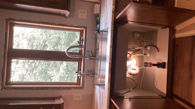 Completed comprehensive kitchen plumbing installation including customer-supplied kitchen faucet, sink basket, and drain connections. Ran refrigerator water supply line through cabinetry and installed shutoff valves for reverse osmosis system, kitchen faucet, and dishwasher. Flared gas line connection to fireplace and performed leak detection testing to verify system integrity, with all connections confirmed secure and operational.