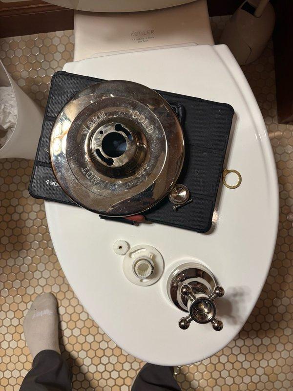 Responded to shower fixture repair call and attempted to reinstall the existing Kohler handle, but discovered the plastic retention piece that secures the handle to the valve stem had broken off and was beyond repair. Removed all existing trim components to expose the valve body and identified the unit as a Kohler Tempress II valve. Documented the valve model with photographs and provided reference images to facilitate sourcing of compatible replacement trim kit in chrome or brushed nickel finish, as color matching is not a priority for the customer.