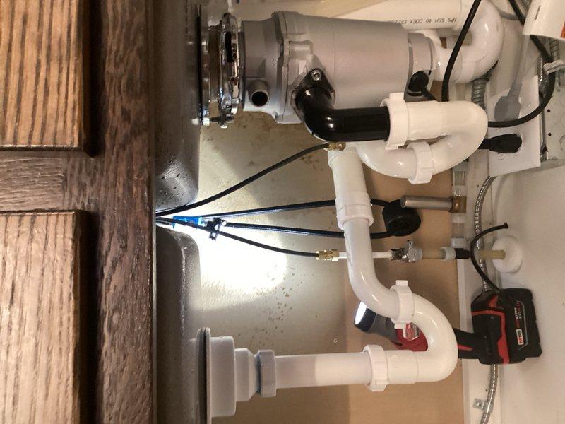 Responded to multiple leak emergency under kitchen sink. Upon arrival, identified active water leaks from three sources: dishwasher connection, kitchen faucet, and disconnected high-pressure supply hose. Shut off water supply to prevent further damage. Diagnosed internal faucet failure as primary cause of leaking. Secured disconnected supply hose and addressed dishwasher connection leak. Documented existing plumbing configuration including garbage disposal, P-trap assembly, and shut-off valves. Provided estimate for complete faucet replacement to resolve internal component failure and prevent future leaks.