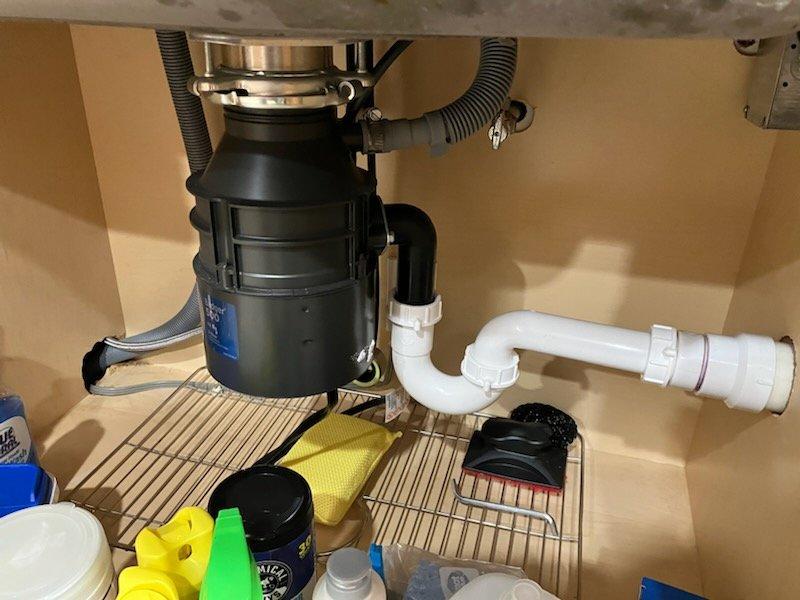 Completed installation of customer-supplied Kohler pull-down kitchen faucet and Badger 500 garbage disposal unit. Removed existing fixtures, installed new disposal with proper mounting assembly and drain connections, connected corrugated drain hose with secure metal clamps, and configured white PVC P-trap drainage system to code. All connections tested for proper operation and leaks, with no issues detected upon completion.