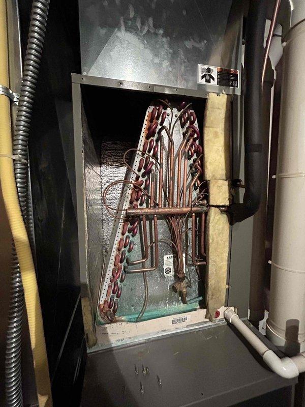 Completed comprehensive air conditioning maintenance tune-up on 14-year-old system. Inspected and tested capacitor and contactor, confirming both components operating within manufacturer specifications. Removed condenser coil access panels and performed coil cleaning by rinsing with water to remove debris and improve heat transfer efficiency. Verified new air filter installed, measured 20-degree temperature split across evaporator coil indicating proper refrigerant charge and airflow, confirmed evaporator coil sweating uniformly throughout, and checked condensate drain line for proper drainage with no blockages detected. All system components functioning properly with no deficiencies noted.
