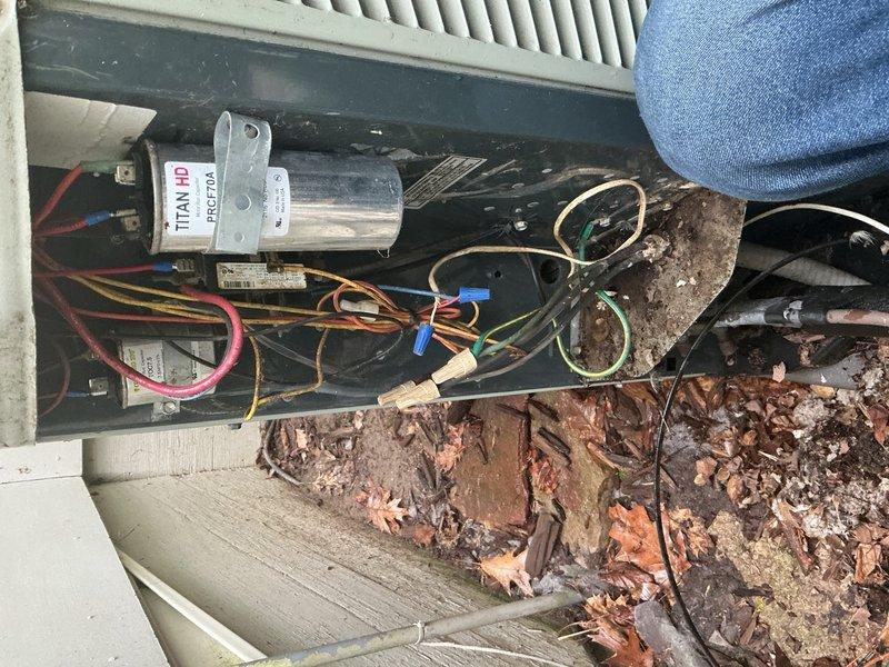 Performed seasonal air conditioning tune-up on residential system of undetermined age. During inspection, discovered the outdoor unit capacitor connections had melted down, creating a safety hazard and preventing proper system operation. Identified significant debris accumulation including organic material and evidence of rodent activity within the outdoor unit cabinet. Documented the failed capacitor with photographs showing heat damage and deteriorated connections on the TITAN HD component. Informed customer of the necessary capacitor replacement and provided estimate for parts and labor to complete the repair.
