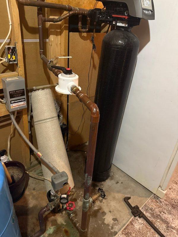 Responded to no water condition in residence caused by broken water filter housing. Customer had damaged the plastic housing while attempting to change filter on Whirlpool WHKFDWHV whole house water treatment system. Removed damaged sediment filter assembly and installed new whole house sediment filter with housing. Restored water supply to home and verified proper system operation. Documented installation with photographs showing complete water treatment setup including sediment filter, pressure tank, copper and PVC piping connections, and control unit.