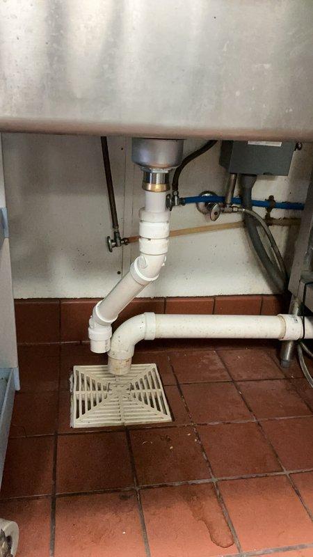 Responded to commercial kitchen plumbing issue where drain piping under food prep sink repeatedly disconnected from the strainer assembly. Upon inspection, determined the sink strainer was defective and causing the piping failure. Replaced the faulty strainer basket and reinstalled the P-trap configuration with new PVC drain piping to ensure secure, leak-free connections. System tested and confirmed operational with no further disconnections.