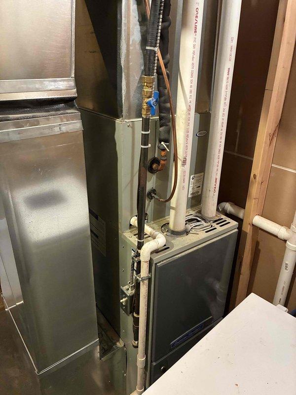 Responded to no cooling complaint on 13-year-old central air conditioning system. Found condenser not running despite 24V present at unit but not reaching contactor. Diagnosed low pressure switch open with system resting at 60 PSI, indicating significant refrigerant loss. Upon inspection, discovered evaporator coil leak evidenced by oil-soaked fitting on evaporator and oil present in condensate drainage. Furnace blower exhibited abnormal noise during operation. System determined to be approximately 5 pounds low on refrigerant from total capacity of 5 pounds 9 ounces plus line set (estimated 6 pounds total). Confirmed active leak at evaporator coil but advised additional leak detection with refrigerant and dye would be necessary to rule out multiple leak points. Provided options for refrigerant recharge with dye testing and evaporator coil replacement. Customer declined repairs and requested second opinion.
