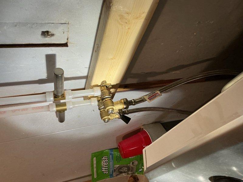 Responded to a leak at washing machine hookup connections previously installed approximately seven months prior. Upon inspection, discovered the cold water supply line fitting was loose at the connection point. Disassembled the cold side connection, applied fresh Teflon tape and pipe dope to threads, and properly reassembled the fitting. Tested system for leaks and verified secure, watertight connection. Advised that if leaking recurs, wall-mounted drop ells will require replacement.