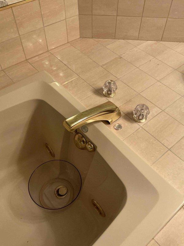 Responded to service call for leaking bathroom fixtures including a Roman tub spigot and vanity faucet with dripping issues. Upon inspection, identified failed cartridge in the Roman tub faucet and oversplashing condition at the vanity sink with gold-finished fixtures and crystal knob handles. Provided estimate for cartridge replacement on both fixtures and performed cleaning of the tiled countertop surface to remove water deposits and staining.
