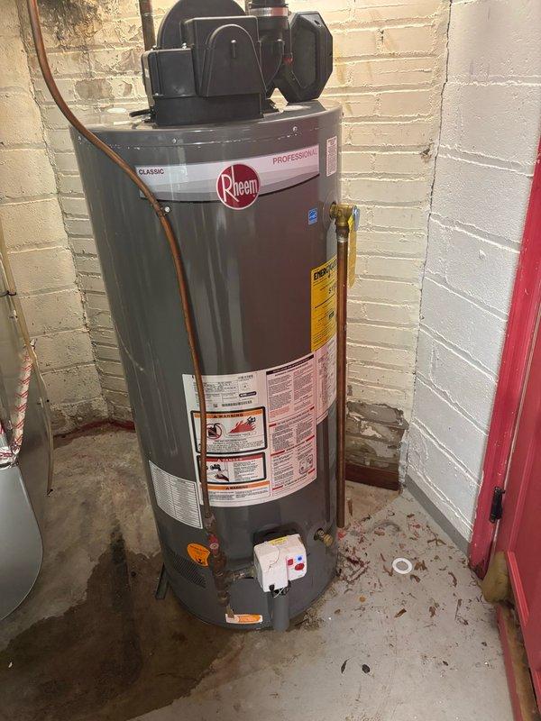 Responded to urgent water leak in furnace room affecting Rheem water heater and surrounding mechanical equipment. Upon arrival, water supply was already shut off by homeowner. Conducted systematic pressure test by slowly restoring water supply to identify leak source among multiple suspected areas. Located pinhole leak on hot water outlet pipe of water heater that had been spraying water throughout the mechanical room. Shut off water supply and performed repair by cutting out compromised section of copper piping and installing coupling to restore pipe integrity. Restored water supply and conducted 15-minute pressure monitoring to verify repair and check for additional leaks. No further leaks detected. Relit water heater pilot and verified proper operation before restoring system to full service.