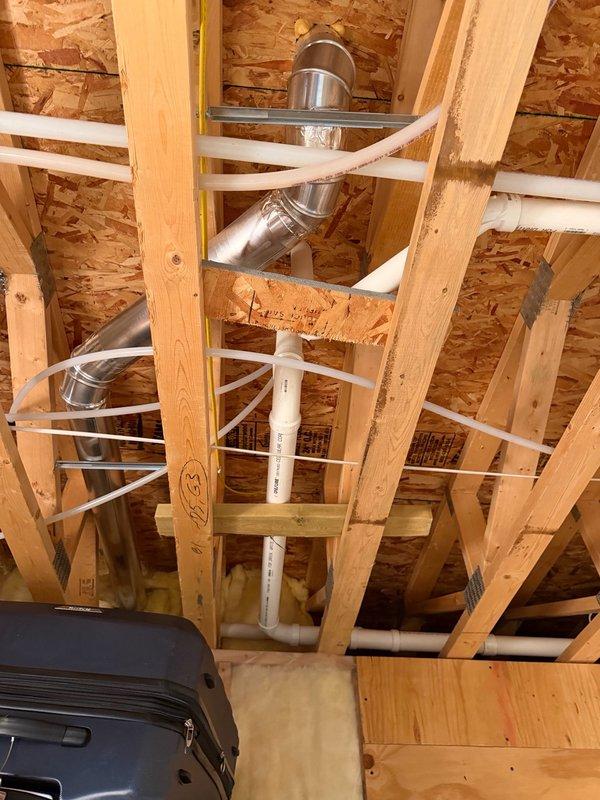 Completed comprehensive plumbing inspection of rough-in installation including PVC drain and vent piping systems in framed ceiling space, HVAC ductwork clearances, and well water pressure tank system with associated copper piping, brass fittings, pressure gauge, and PEX connections. All components inspected for proper installation, code compliance, and operational readiness prior to finish work.
