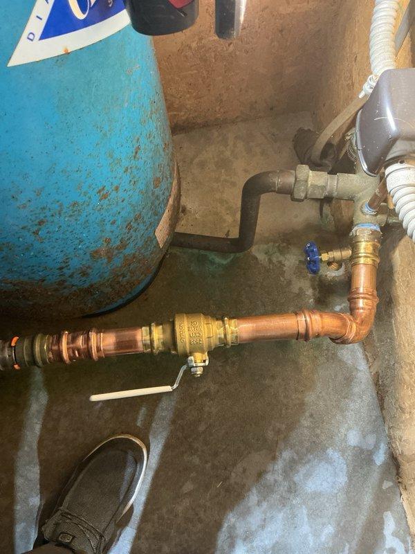 Responded to a callback for a leaking main water line at the crimp connection. Upon arrival, identified an additional issue with a ball valve leaking near the pressure tank. Replaced the defective ball valve with a new unit, resolving both the dripping condition and ensuring proper system operation. Documented the completed repairs with photos showing the pressure tank assembly and updated copper piping configuration with new valve installation.
