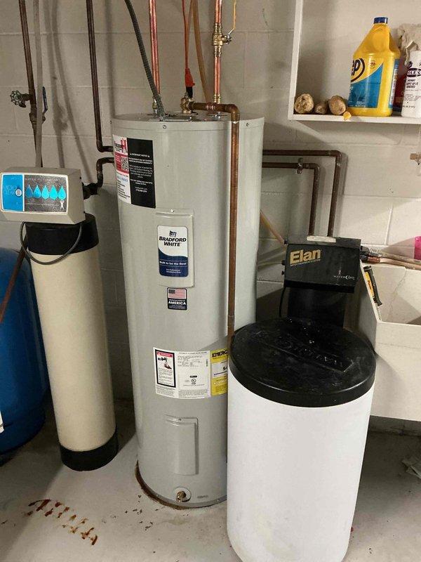 Responded to service call for leaking water heater in residential basement utility area. Upon arrival, confirmed existing water heater was actively leaking and required immediate replacement. Successfully removed old unit and installed new Bradford White 50-gallon electric water heater. Connected all copper supply and discharge piping to existing plumbing infrastructure, ensuring proper integration with adjacent water softener and Elan water treatment system. Installed appropriate shut-off valves and verified all connections for proper seal and operation. Tested new water heater for functionality, confirmed no leaks at any connection points, and restored hot water service to residence.